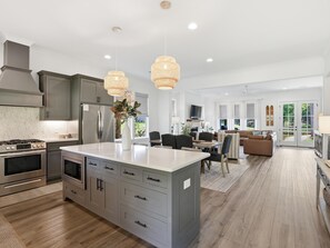 A modern kitchen with a large island, stainless steel appliances, and pendant lighting. - Lakefront home. Beach. Kayaks. Dock. Outdoor fireplace & TV. Neighborhood Pool. (Dadeville)