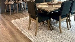 Eine moderne Küche mit einer zentralen Kochinsel, Pendelleuchten und einem Essbereich mit Holztisch und Stühlen.