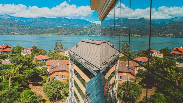 Un immeuble de grande hauteur, doté d’une façade en verre, qui offre une vue sur un lac et des montagnes.