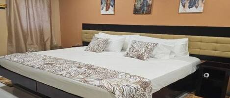 A bedroom with a bed, a headboard, a nightstand, an air conditioner, and a curtain.