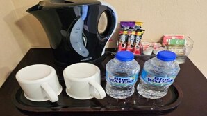 A tray with a coffee maker, two white mugs, and two bottles of water. - Beres Vale Apartments - King Room
 (Castara)