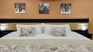 A hotel room with a bed, two nightstands, and three wall-mounted artworks. - Beres Vale Apartments - King Room
 (Castara)