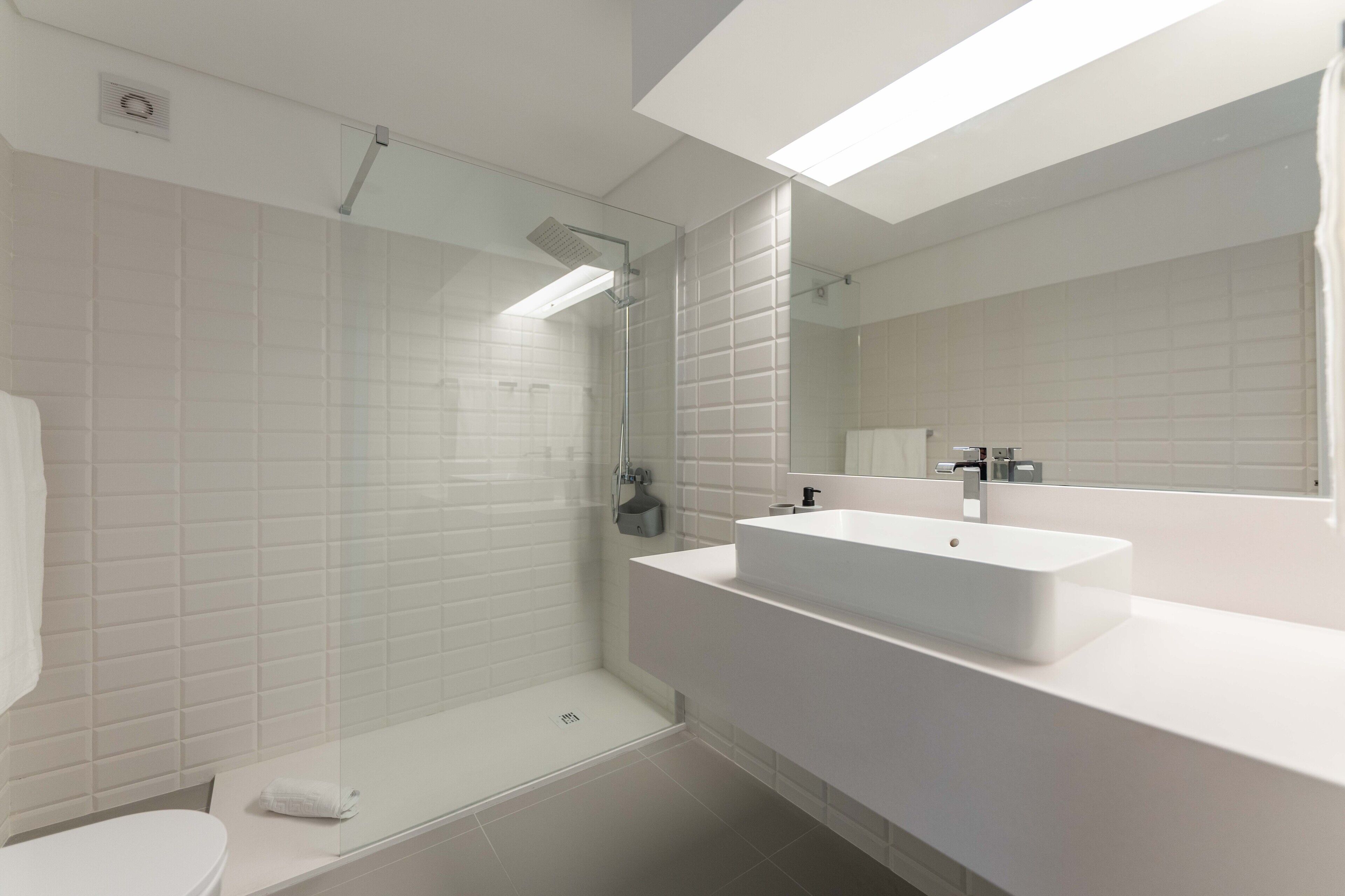 Signature appartement | Badkamer | Een douche, een haardroger, een bidet, handdoeken