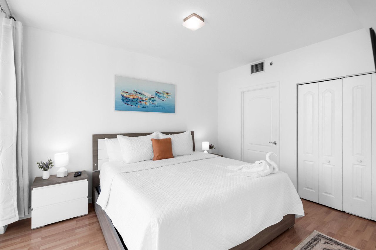 A hotel room with a bed, nightstand, and a painting on the wall.