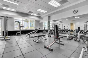 A gym with various exercise equipment, large windows, and a clock on the wall. - Spacious 2 Bed Unit in Brickell with Free Parking (Miami)