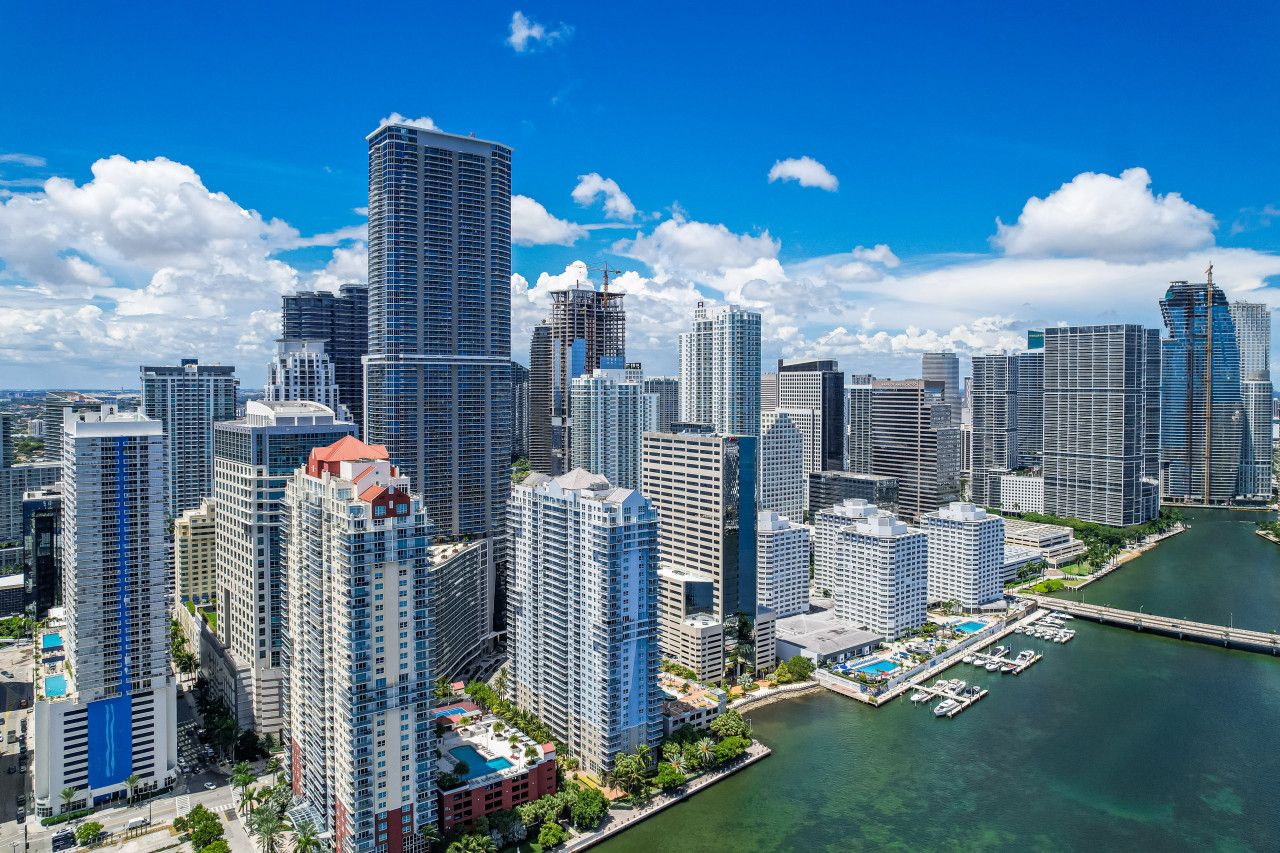 A high-rise urban area with modern buildings, a marina, and a river.
