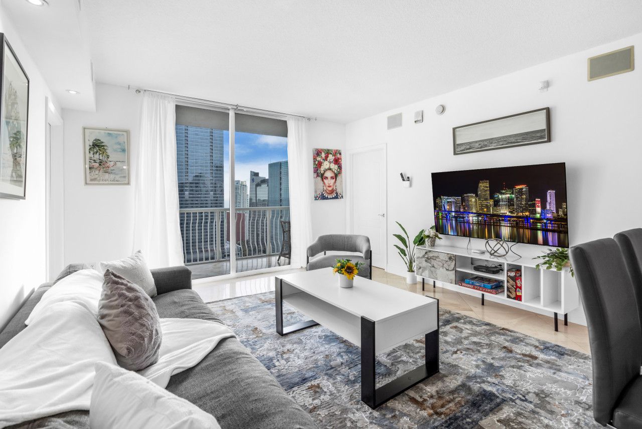 A modern living room with a large window, a flat-screen TV, a sofa, and a coffee table.