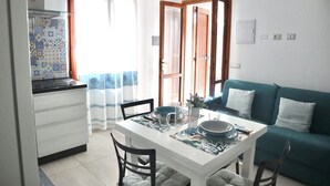 A compact living space with a kitchenette, dining area, and a green sofa. - Curated cottage within walking distance of the sea (Agrustos)