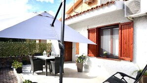 An outdoor patio with a table and chairs, a large umbrella, and potted plants. - Curated cottage within walking distance of the sea (Agrustos)