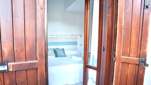 A bedroom with a bed, a headboard, and a wooden door. - Curated cottage within walking distance of the sea (Agrustos)