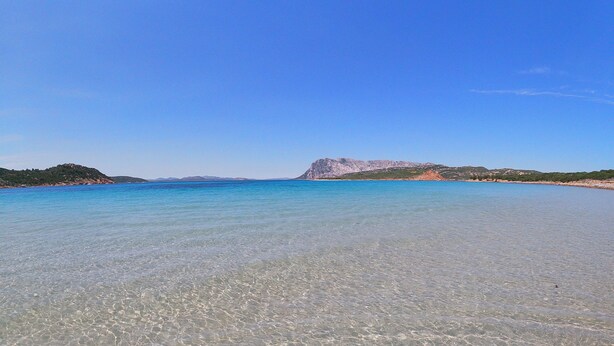 A clear beach with calm waters and a distant rocky hill. - Curated cottage within walking distance of the sea (Agrustos)
