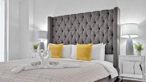A neatly made bed with a tufted headboard, white and yellow pillows, and a swan-shaped towel arrangement. - Amazing 1 Bed in Brickell key W/ FREE PKG (Miami)