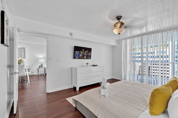 A bedroom with a bed, a white dresser, a painting on the wall, and a view through the window. - Amazing 1 Bed in Brickell key W/ FREE PKG (Miami)