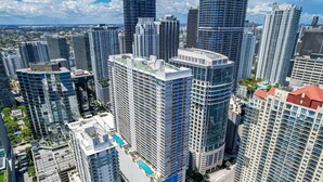 A high-rise urban area with modern buildings, including a prominent building with a blue stripe and a rooftop pool. - Amazing 1 Bed in Brickell key W/ FREE PKG (Miami)