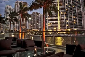 A rooftop bar with seating and a view of high-rise buildings and a body of water. - Amazing 1 Bed in Brickell key W/ FREE PKG (Miami)