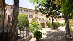 Une cour avec une statue, une fontaine et un bâtiment doté de balcons.