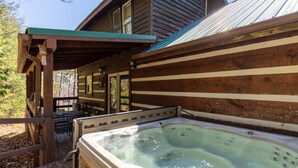 Eine Holzhütte mit Whirlpool und Sitzbereich im Freien.