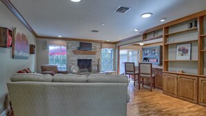 A spacious living room with a large sofa, a fireplace, wooden flooring, and built-in shelving. - 3/2 Ocala Home, Historic District and Town Sq. (Ocala)