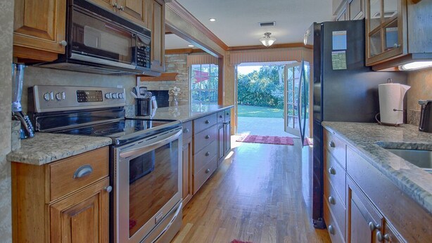 A kitchen with wooden cabinets, stainless steel appliances, and a view to the outdoors. - 3/2 Ocala Home, Historic District and Town Sq. (Ocala)