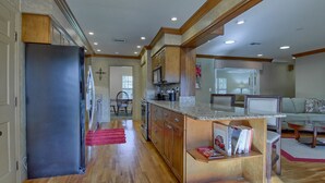 A spacious kitchen with wooden cabinets, a refrigerator, and a countertop with a magazine. - 3/2 Ocala Home, Historic District and Town Sq. (Ocala)