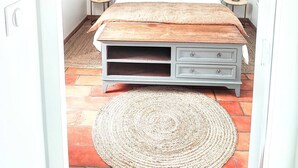A bedroom with a stone wall, a bed with a wooden headboard, two bedside tables, and a woven rug on the floor. - Charming house 100 mt from the famous "La Torche" beach

 (Plomeur)