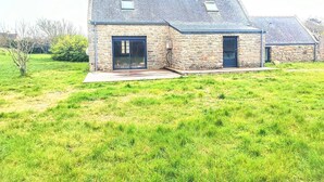 A stone house with a sloped roof, a front door, and a small window. - Charming house 100 mt from the famous "La Torche" beach

 (Plomeur)