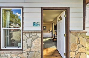 A stone-framed entrance to a building with a 'Welcome to the Angler's Alibi' sign, a hallway leading to a room with a bed and a nightstand, and a door with a glass panel.
