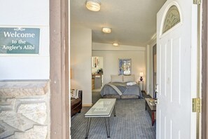 Et hotelværelse med seng, skrivebord, stol, lampe og en velkomstskilt.