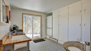 A modern kitchen with a large window, white cabinets, and a dining area with a round table.