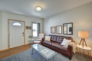 A living room with a brown leather sofa, a glass coffee table, a lamp, and a door with a window.