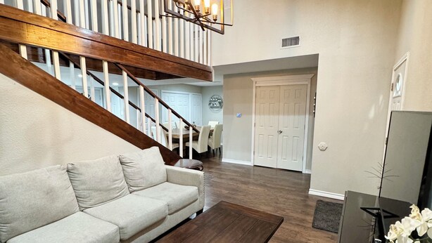 A modern living room with a sectional sofa, a coffee table, a TV stand, and a staircase with a railing. - Waco Farm House (Waco)