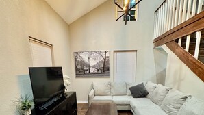 A living room with a sofa, a coffee table, a TV, and a staircase. - Waco Farm House (Waco)