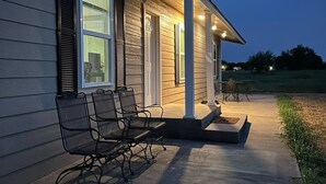 A house with a covered porch, two chairs, and a table. - Waco Farm House (Waco)
