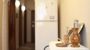 Ein Flur mit einem weißen Kühlschrank und einem Tisch mit einer Vase, einem Salzstreuer und einem Holzkasten.