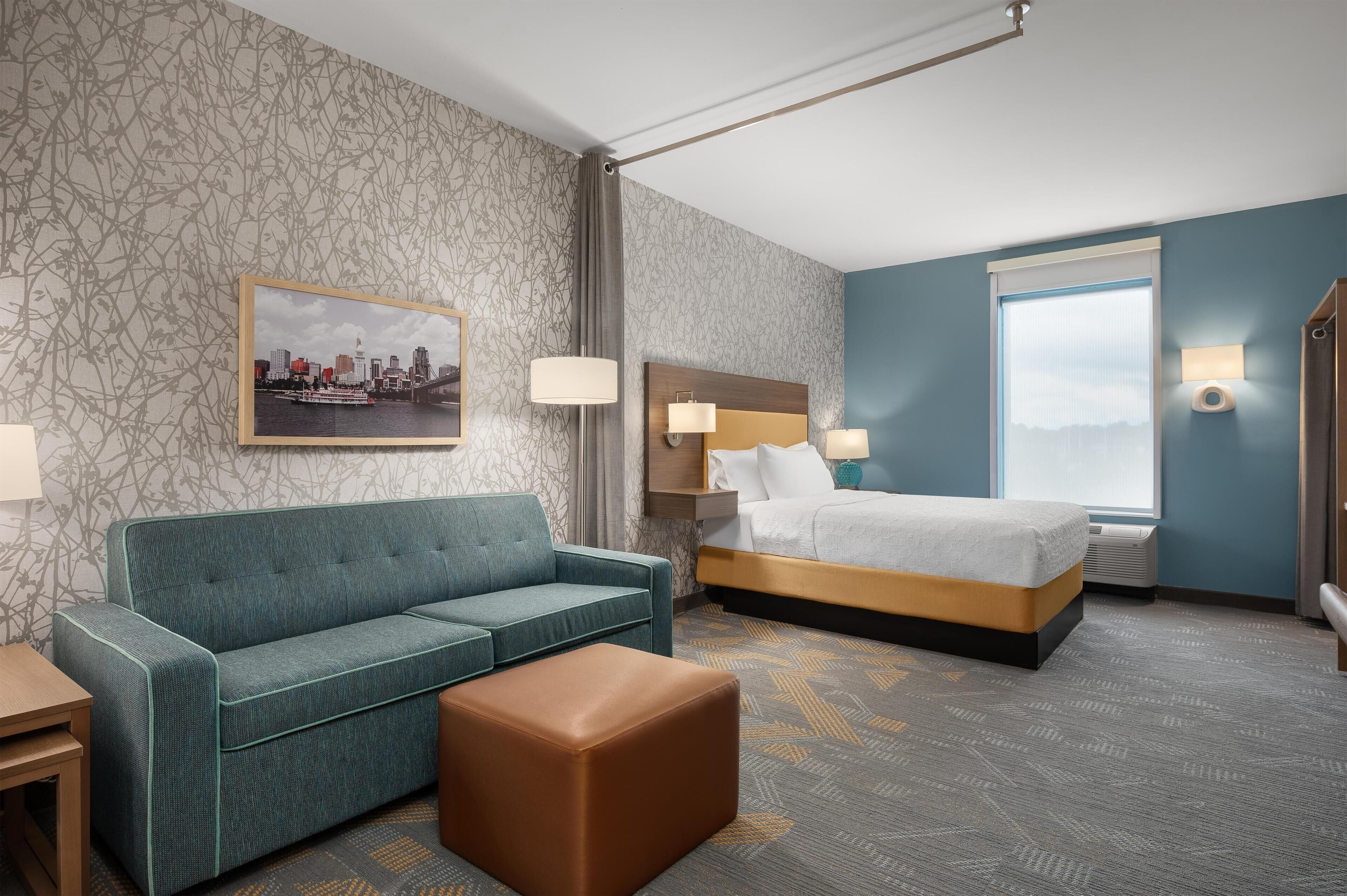 Una camera d'albergo con un letto, un divano, un tavolino e un quadro appeso al muro.