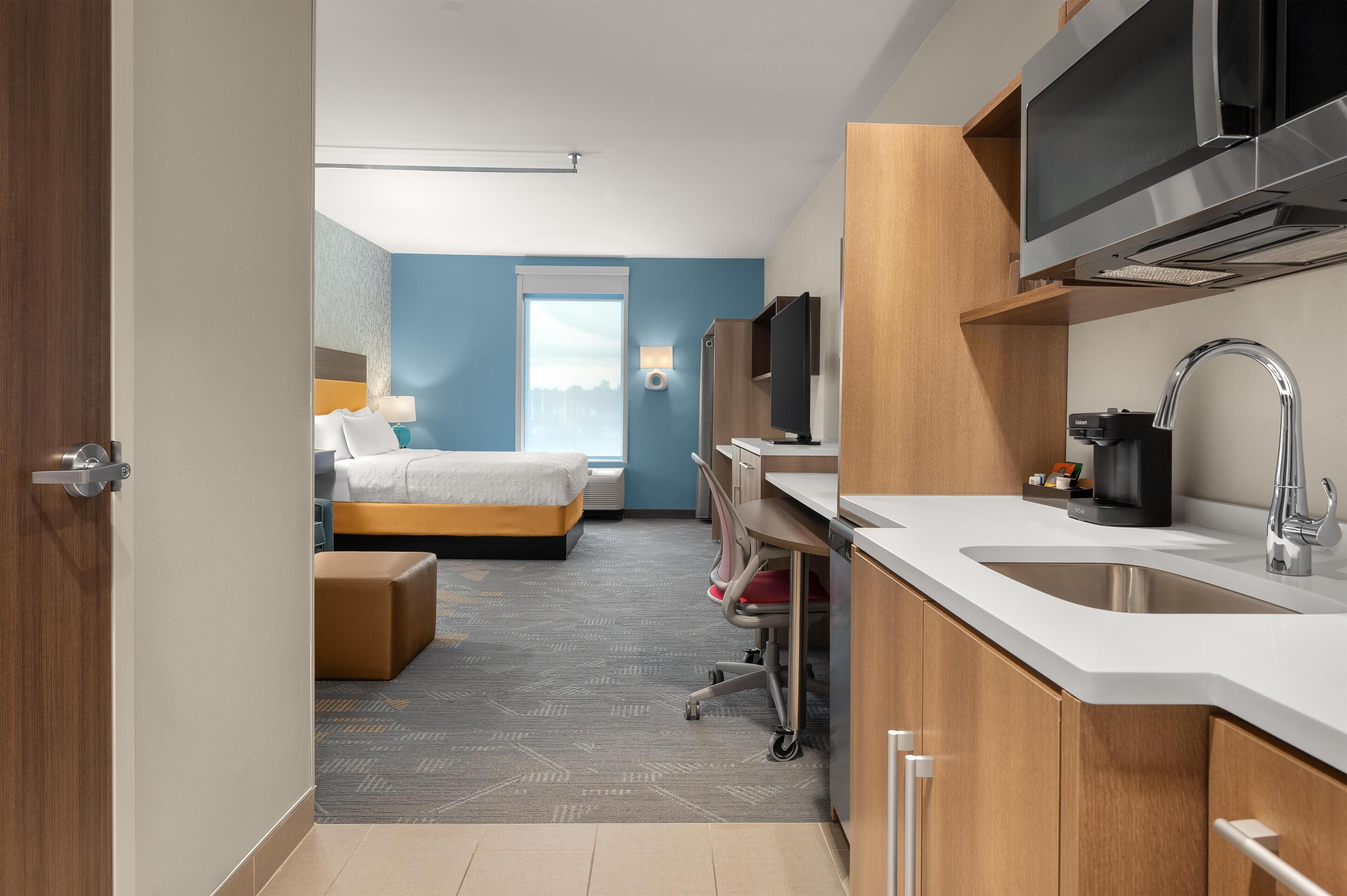 Une chambre d’hôtel moderne équipée d’un lit, d’un bureau et d’une kitchenette.