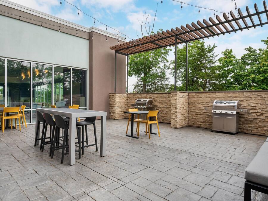 An outdoor patio with a table and chairs, a grill, and a pergola.