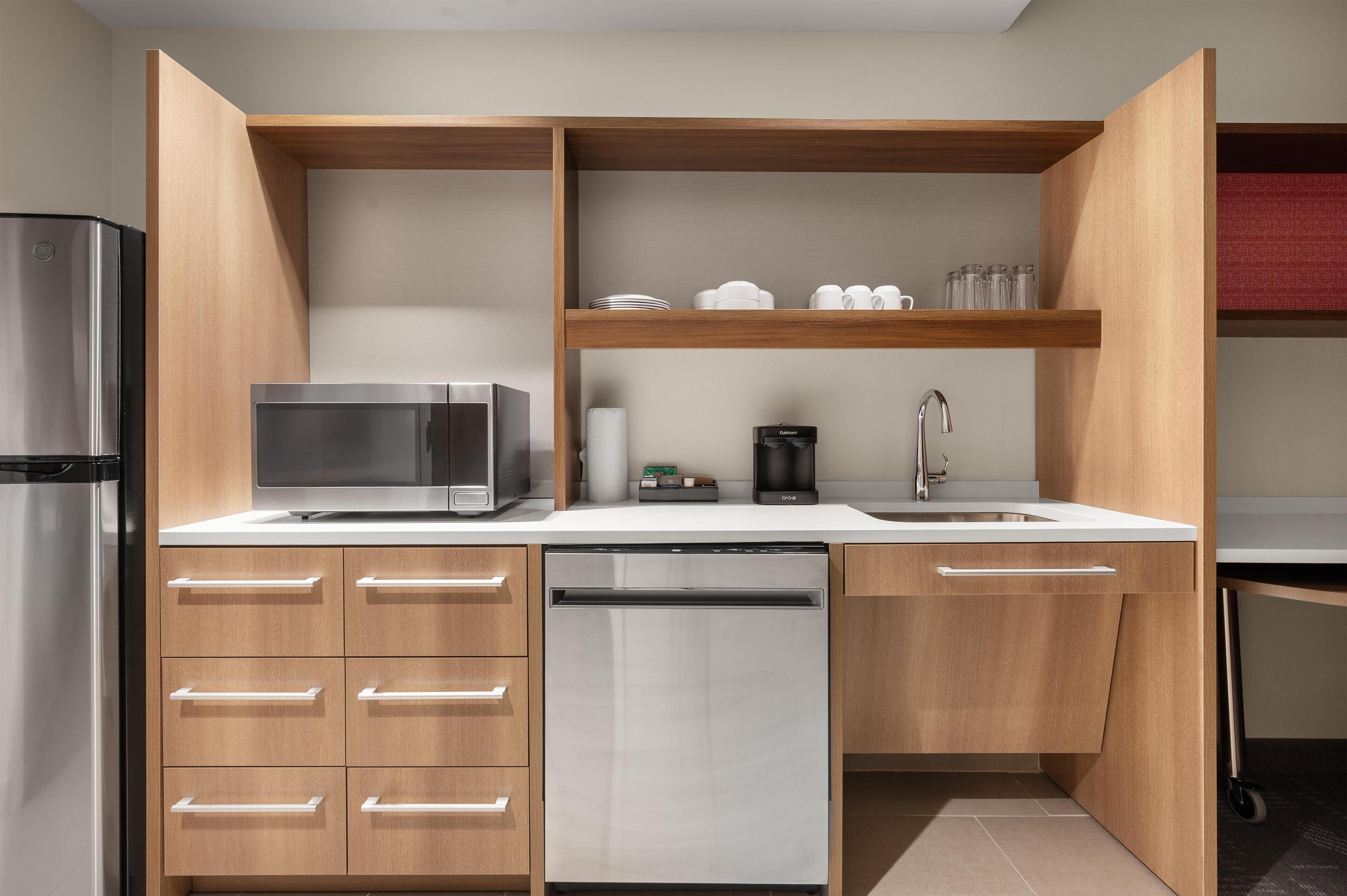 A modern kitchen with a stainless steel refrigerator, microwave, dishwasher, and a coffee maker on the countertop.