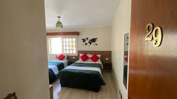 A hotel room with two beds, a wooden door with the number 29, a world map on the wall, and a ceiling fan.