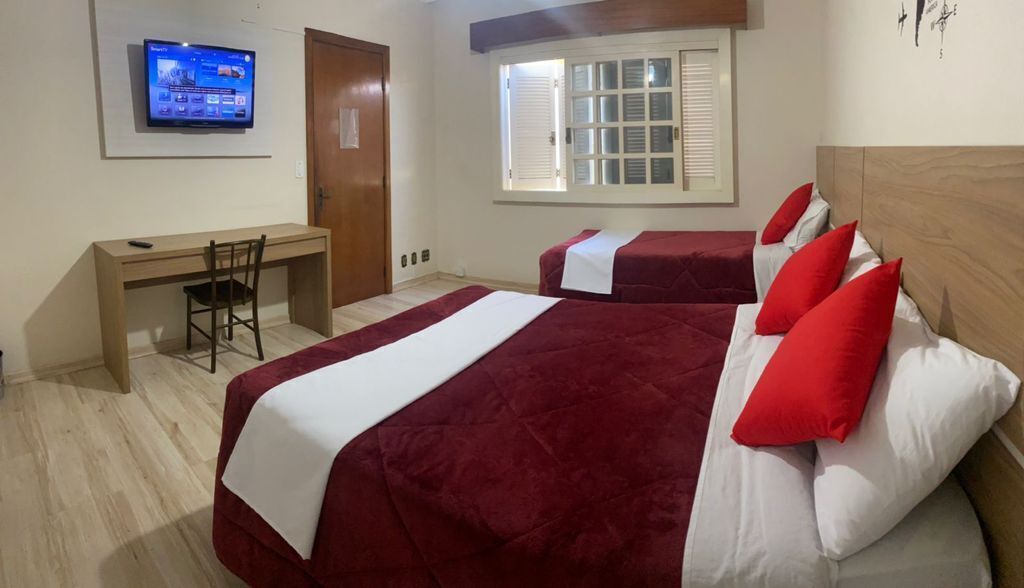 Ein Hotelzimmer mit zwei Betten, einem Schreibtisch und einem Fernseher.