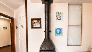 Sala de estar com lareira a lenha, um sofá e uma porta com um número.
