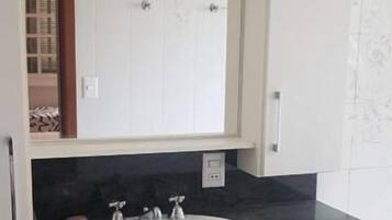 Ein Badezimmer mit einem weißen Waschbecken, einer schwarzen Arbeitsplatte und weißen Schränken.