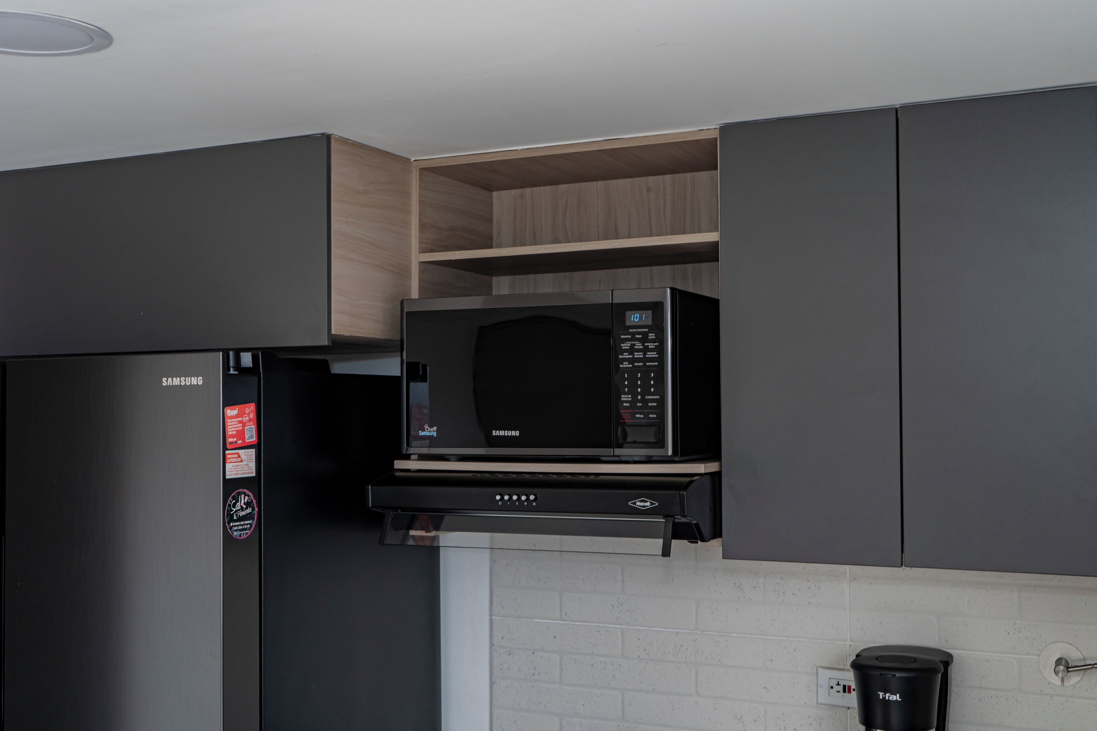 A kitchen with a Samsung microwave, a refrigerator, and a coffee machine.