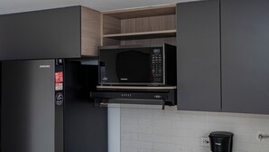 Ett kök med en Samsung-mikrovågsugn, ett kylskåp och en kaffemaskin.
