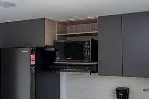 A kitchen with a Samsung microwave, a refrigerator, and a coffee machine. - Apartamento Exclusivo en Laureles (Medellín)