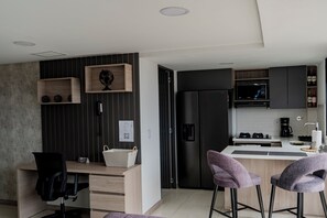 A modern kitchen with a built-in microwave, refrigerator, and bar area. - Apartamento Exclusivo en Laureles (Medellín)