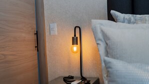 Ett sängbord med en lampa, en fjärrkontroll och ett eluttag.