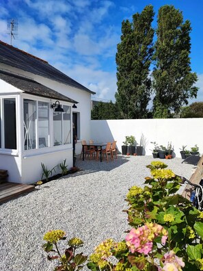 Ein Haus mit Terrasse, Tisch und Stühlen sowie Kübelpflanzen.