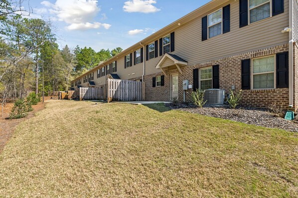 A row of townhouses with a grassy yard and wooden fences.