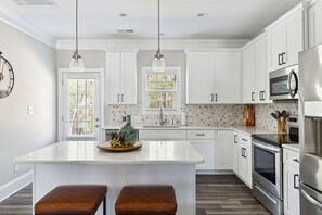 A modern kitchen with white cabinets, stainless steel appliances, and a central island with stools.